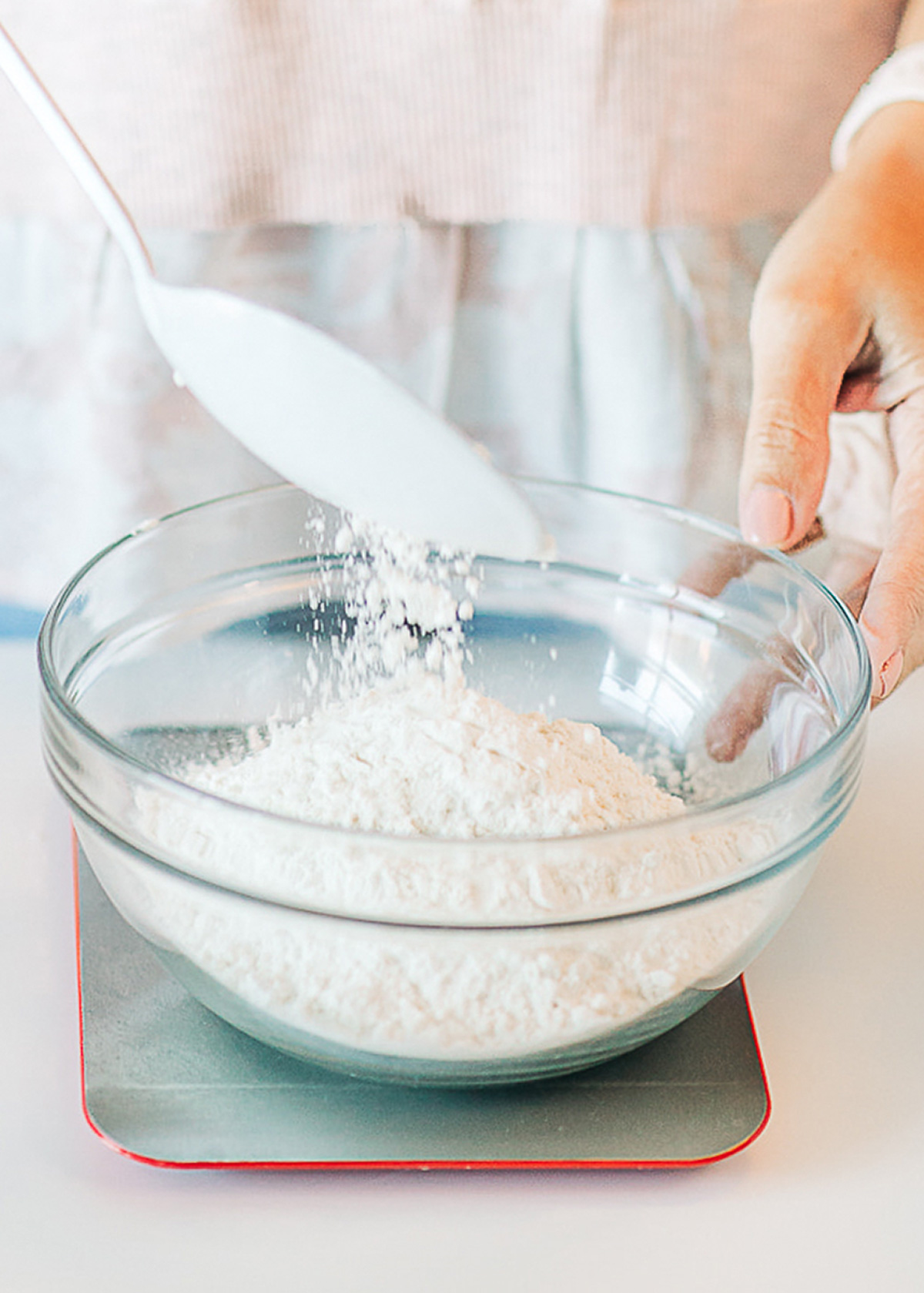 a woman measuring flour with a kitchen scale.