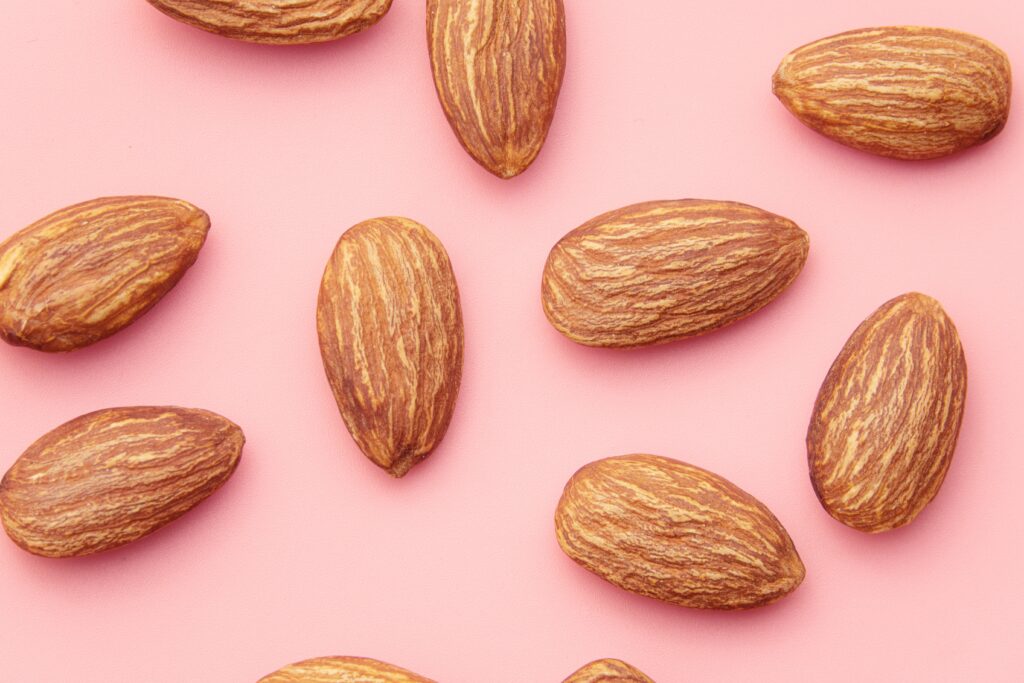 Almonds over a pink surface.