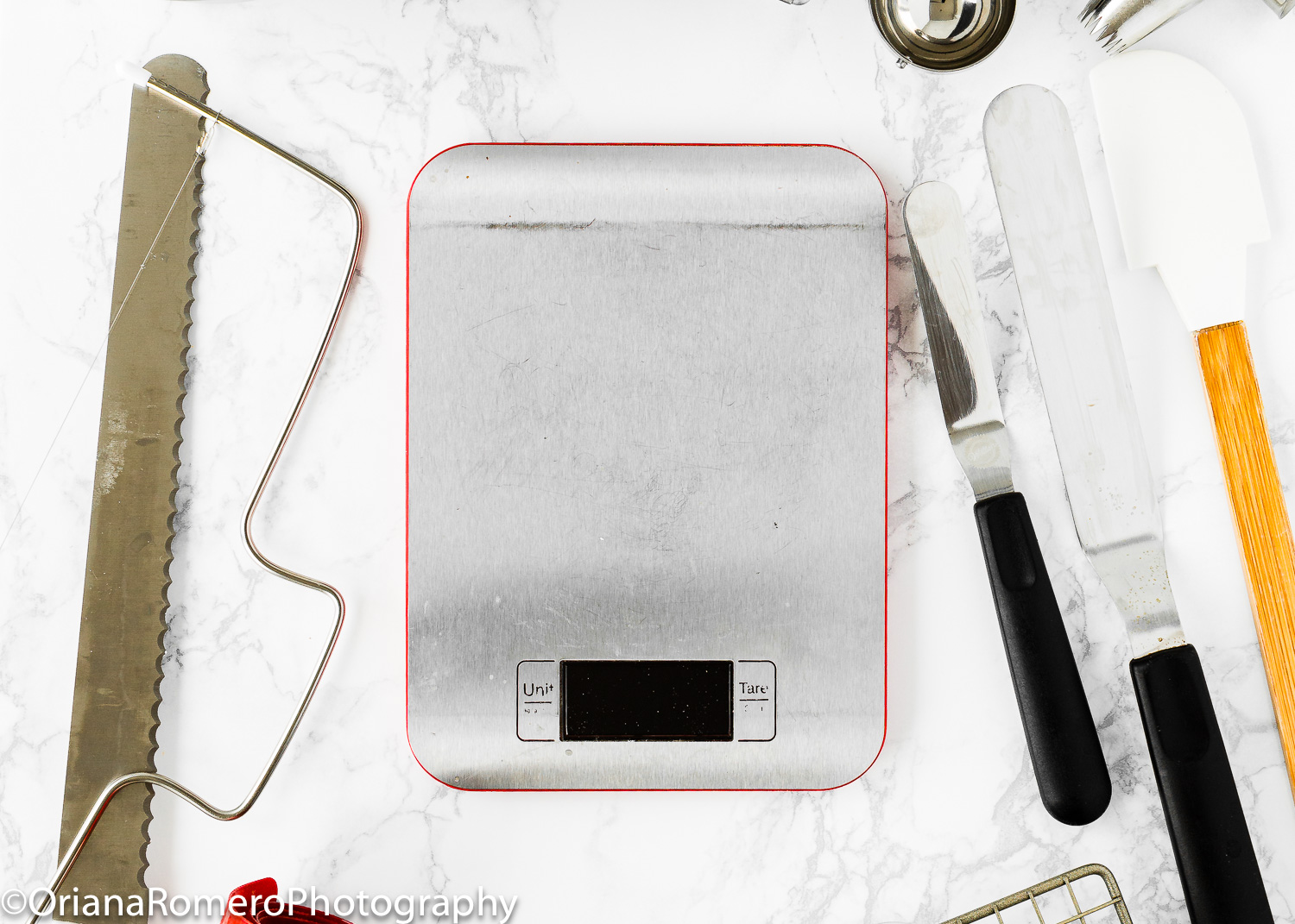 a kitchen scale over a marble surface with other kitchen tools.